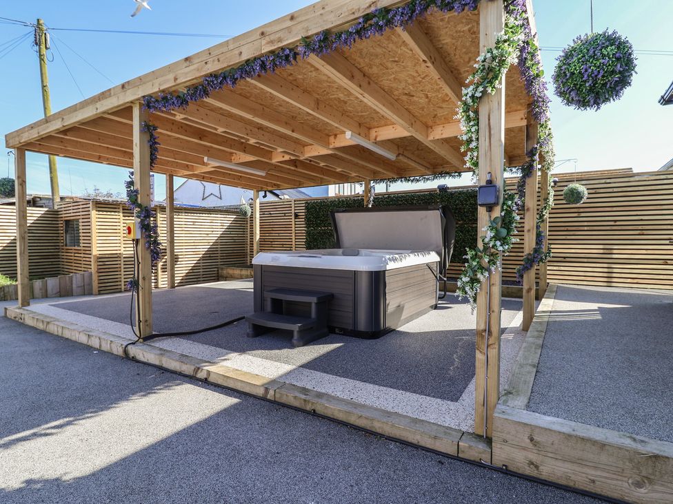 An outdoor area with a hot tub under a wooden structure at 1 Talbot Drive Talacre