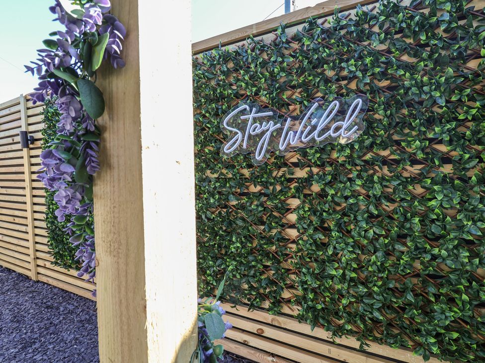 A decorative wall with greenery and a neon sign at 1 Talbot Drive in Talacre