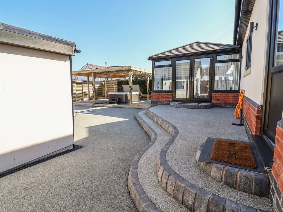 A patio area with a pathway leading to a canopy at 1 Talbot Drive Talacre
