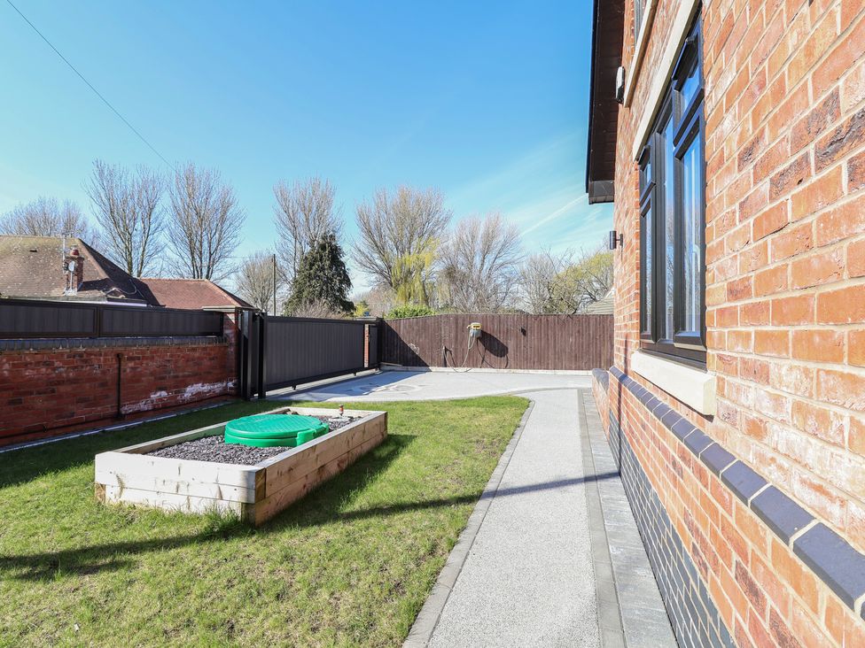 A garden with grass and a raised flower bed at 1 Talbot Drive Talacre