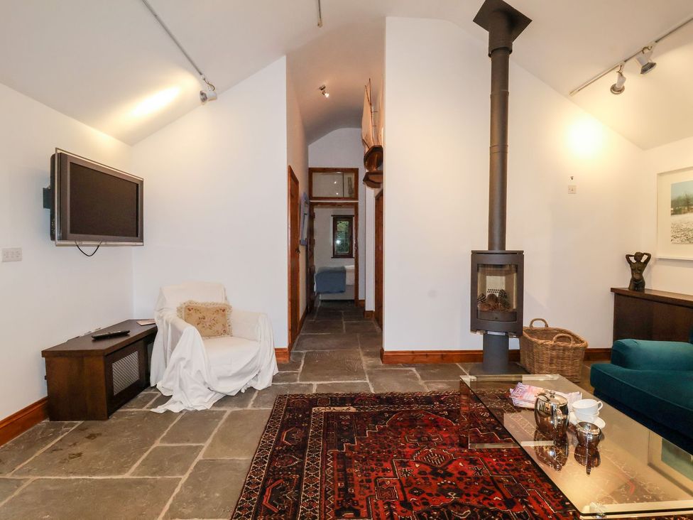 A living room with a television and stove at Owl Cottage in Woodbridge
