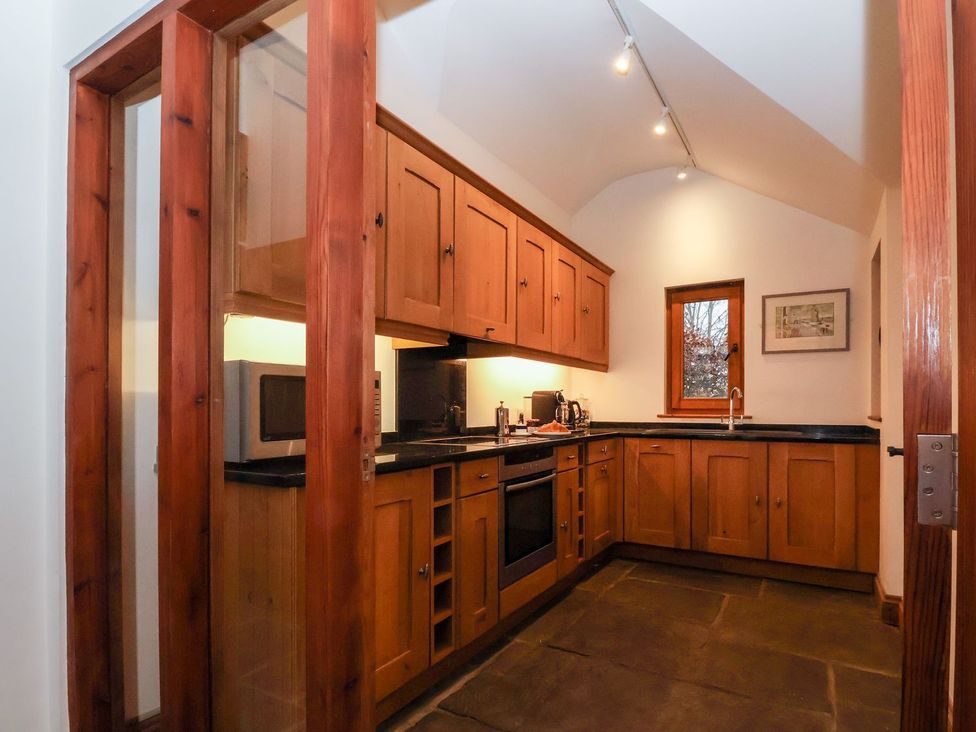 A kitchen with wooden cabinets and appliances at Owl Cottage in Woodbridge