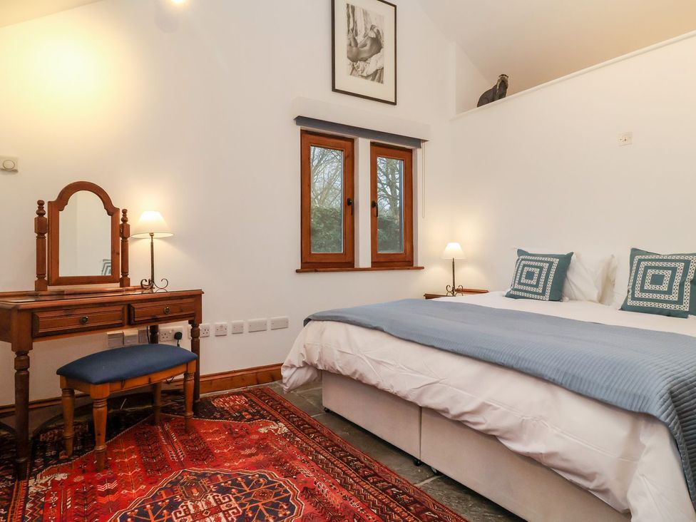 A bedroom with a bed, mirror, and chair at Owl Cottage in Woodbridge