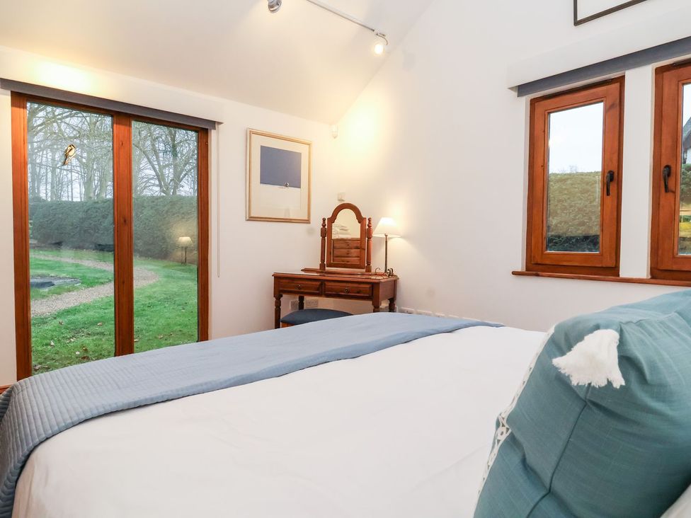 A bedroom with a bed and dressing table at Owl Cottage Woodbridge