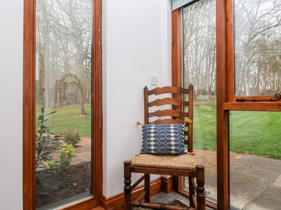 A chair with a pillow beside windows at Owl Cottage in Woodbridge