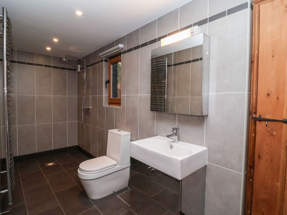 A bathroom with a toilet, sink, shower and mirror at Owl Cottage in Woodbridge
