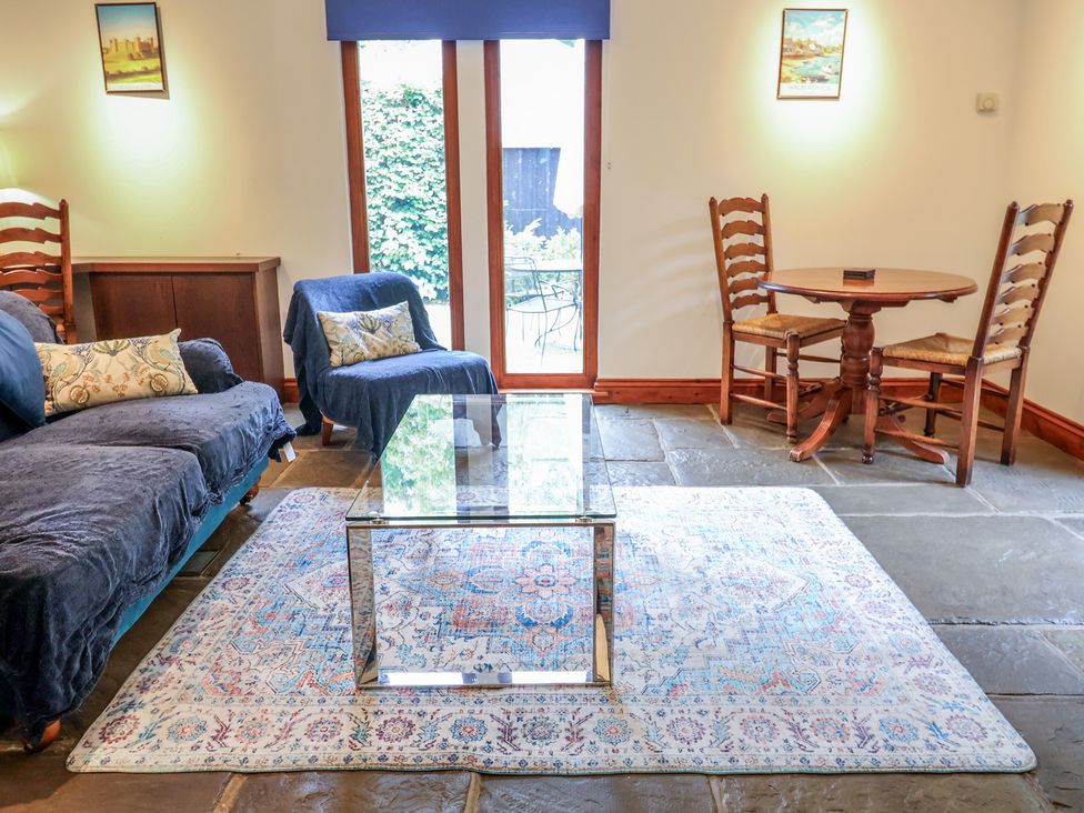A living room with a sofa, coffee table, and dining set at Owl Cottage, Kettleburgh near Framlingham