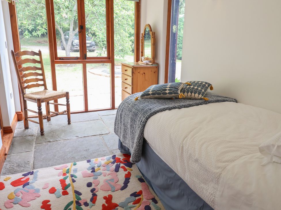 A bedroom with a bed, chair and table at Owl Cottage in Kettleburgh near Framlingham
