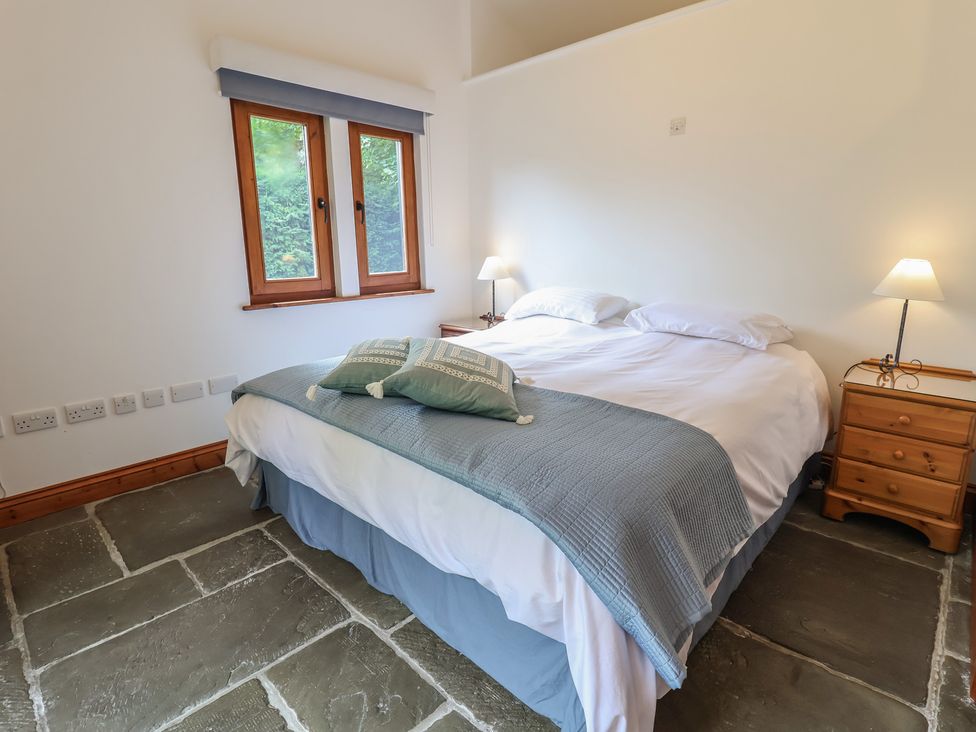 A bedroom with a bed and windows at Owl Cottage in Kettleburgh near Framlingham