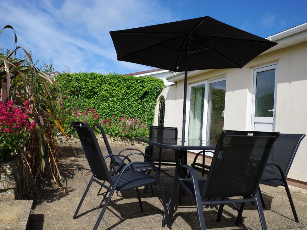 An outdoor seating area with a table and chairs at Badgers Cliff in Polzeath