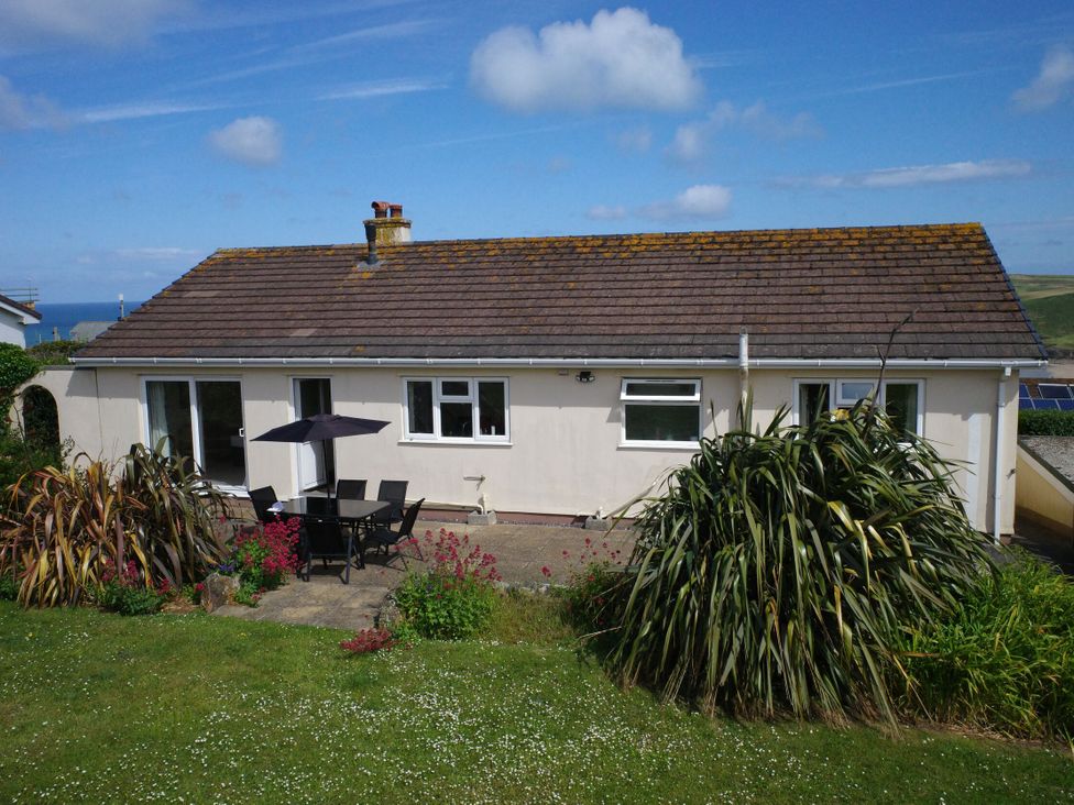 A house with a patio set and plants at Badgers Cliff in Polzeath