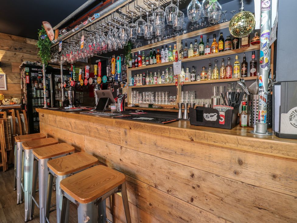 A bar counter with stools and various drinks at Chalet 86 in North Shields