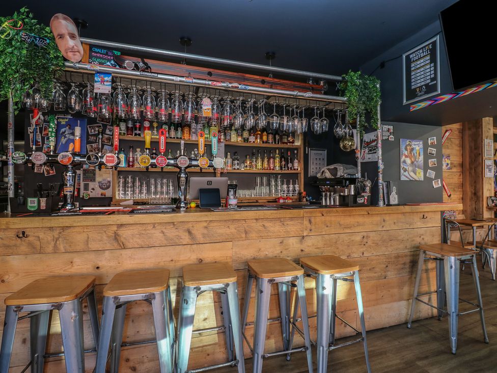 A bar with shelves of bottles and glasses at Chalet 86 in North Shields