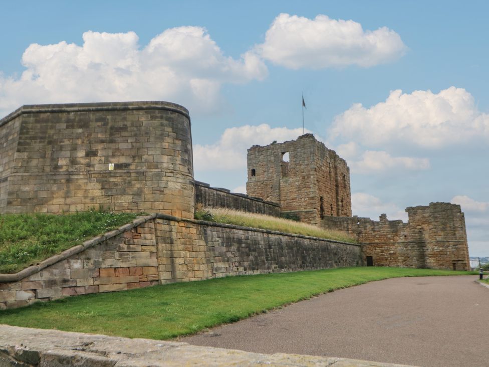 A stone castle wall with flag and pathway at a historical site in North Shields