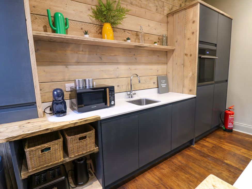 A kitchen with a sink, microwave, and storage baskets at Chalet 86 Tynemouth