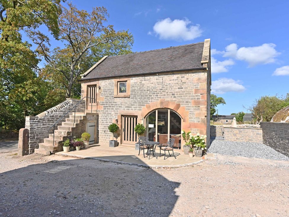 An exterior view of a building with stairs and patio at Lane House Farm Barn Butterton