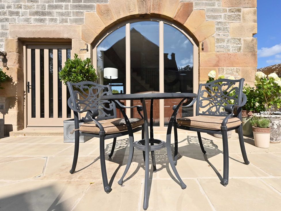 An outdoor seating area with a table and chairs at Lane House Farm Barn in Butterton