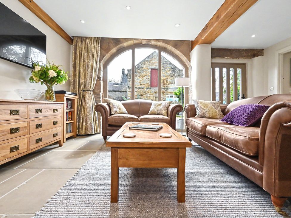A living room with a sofa and coffee table at Lane House Farm Barn in Butterton