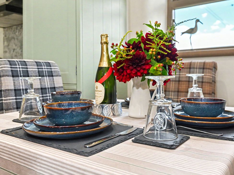 A dining table set with plates, bowls, glasses, and a champagne bottle at Lane House Farm Barn, Butterton