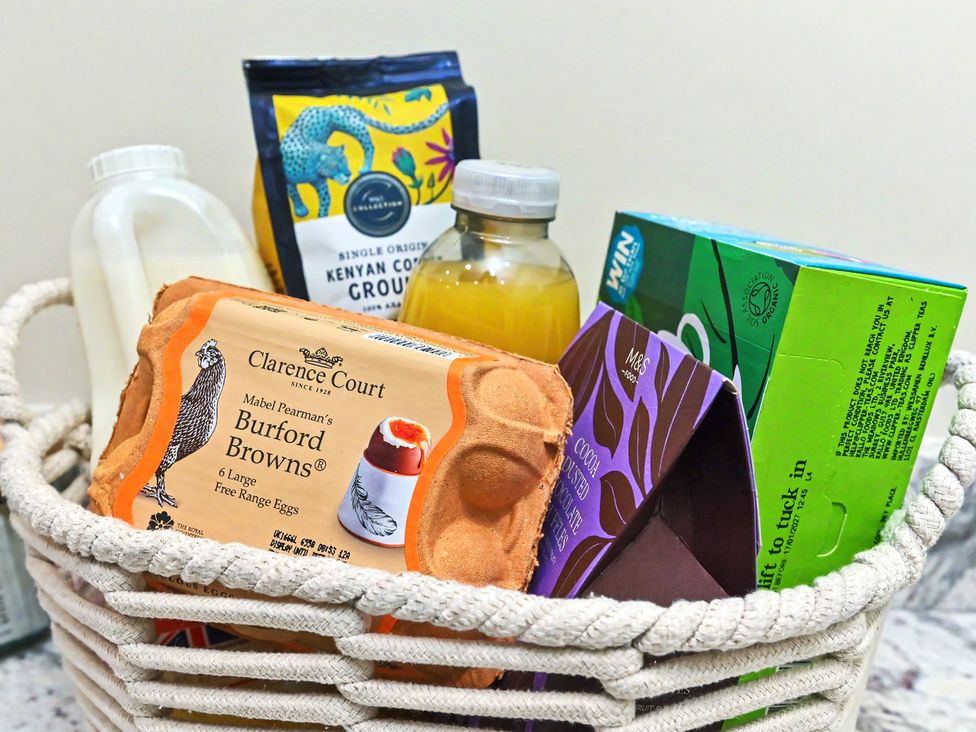 A basket with milk, coffee, orange juice, eggs, chocolate, and tea at Lane House Farm Barn Butterton