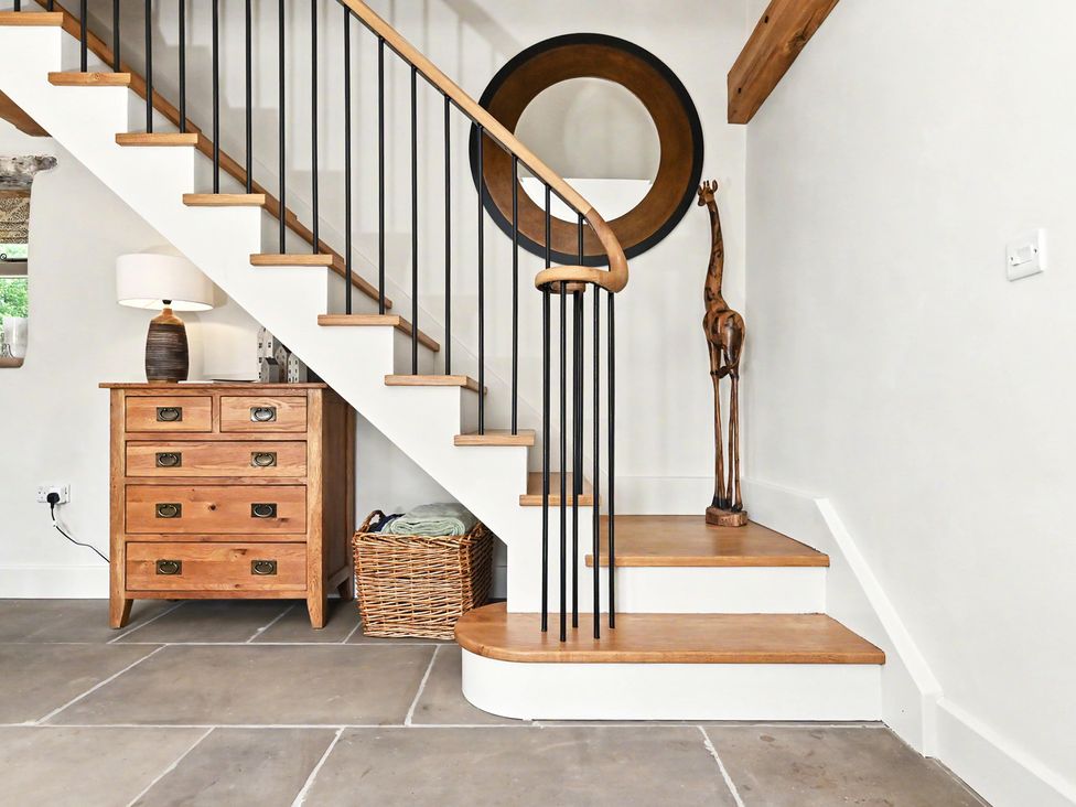 A staircase with wooden steps and a lamp in the entryway at Lane House Farm Barn Butterton