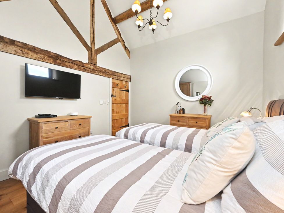 A bedroom with two beds and a television at Lane House Farm Barn in Butterton