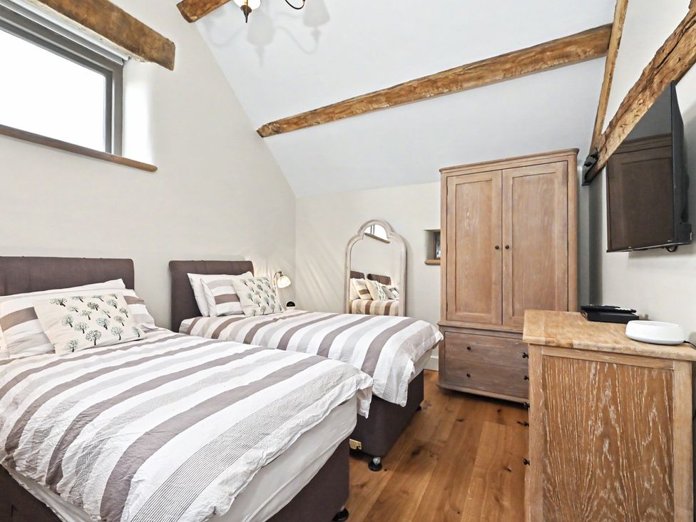 A bedroom with two beds and a wardrobe at Lane House Farm Barn Butterton