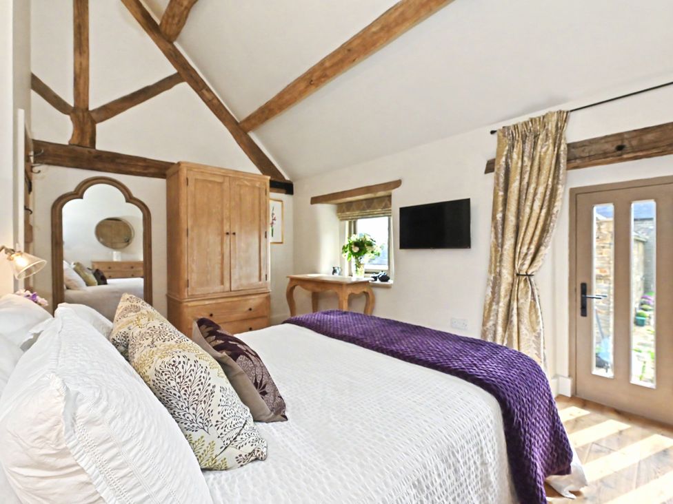 A bedroom with a bed and wardrobe at Lane House Farm Barn Butterton