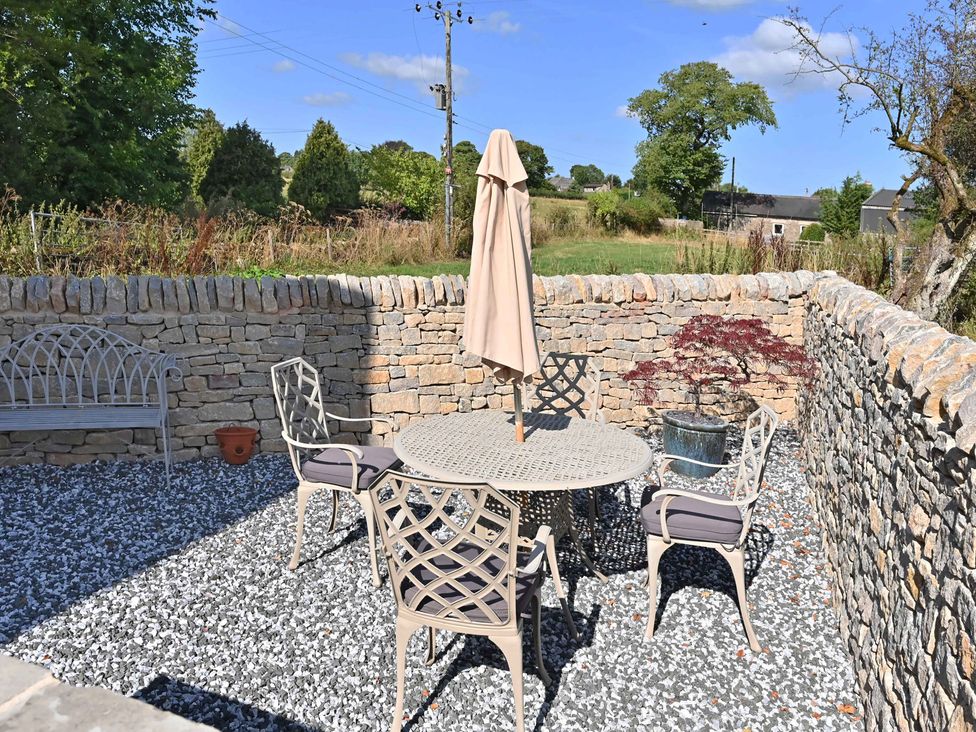 An outdoor patio with a table and chairs at Lane House Farm Barn Butterton