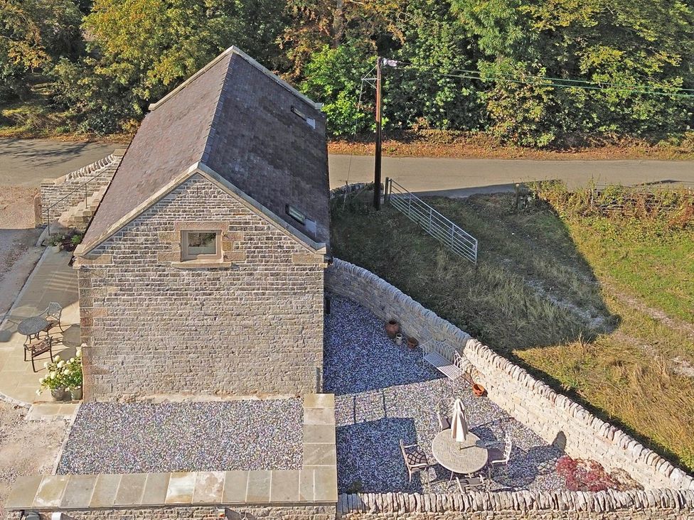 An outdoor area with a stone wall and patio furniture at Lane House Farm Barn Butterton