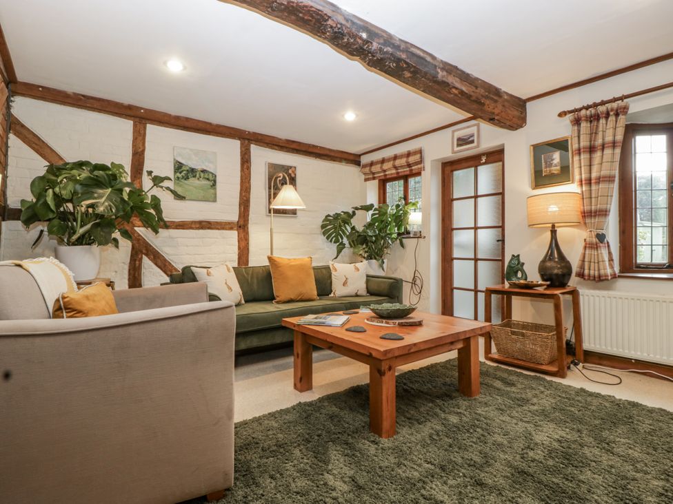 A living room with a sofa, coffee table, and plants at Magpie Cottage in Worcester