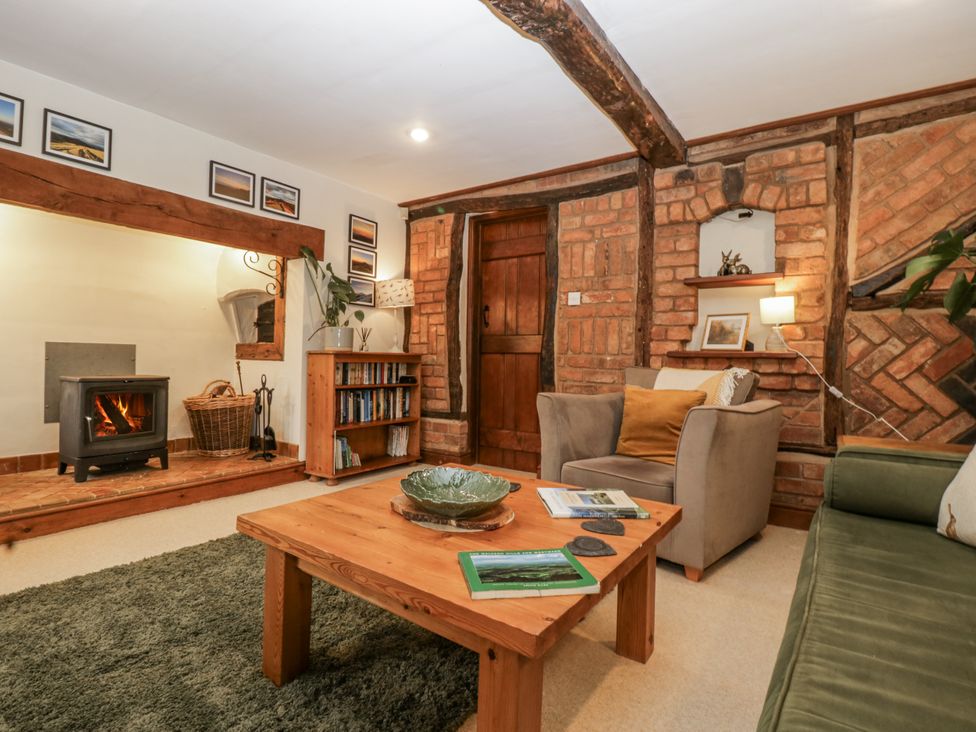 A living room with a stove and bookshelves at Magpie Cottage in Worcester