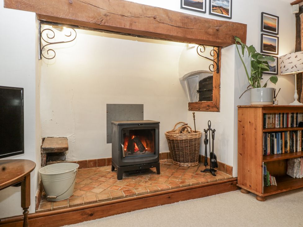 A living room with a fireplace and shelving at Magpie Cottage Worcester