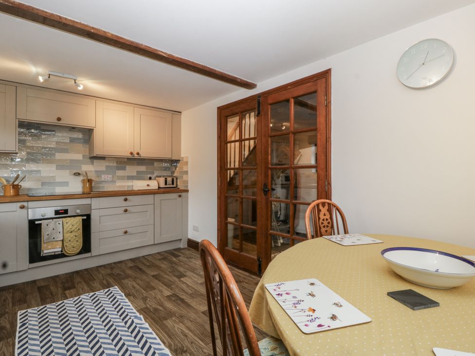A kitchen with cabinets, oven, and table at Magpie Cottage in Worcester