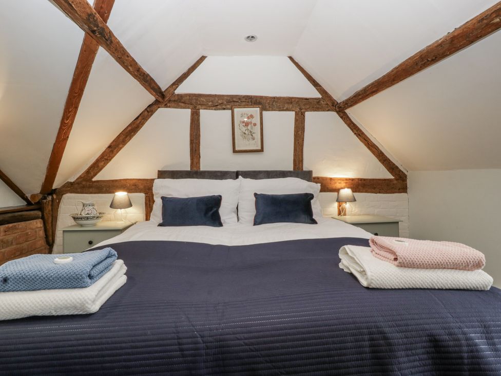 A bedroom with a bed and bedside tables at Magpie Cottage Worcester
