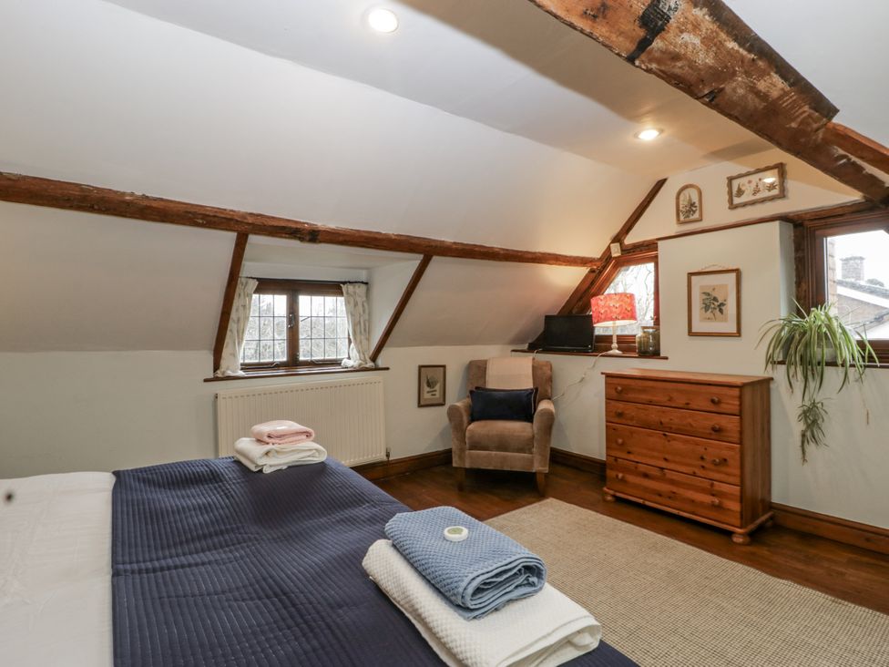 A bedroom with a bed and a chair at Magpie Cottage in Worcester