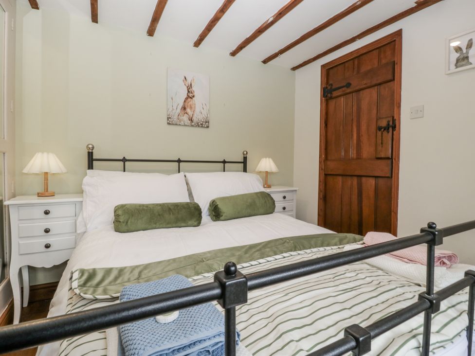 A bedroom with a bed and nightstand at Magpie Cottage in Worcester
