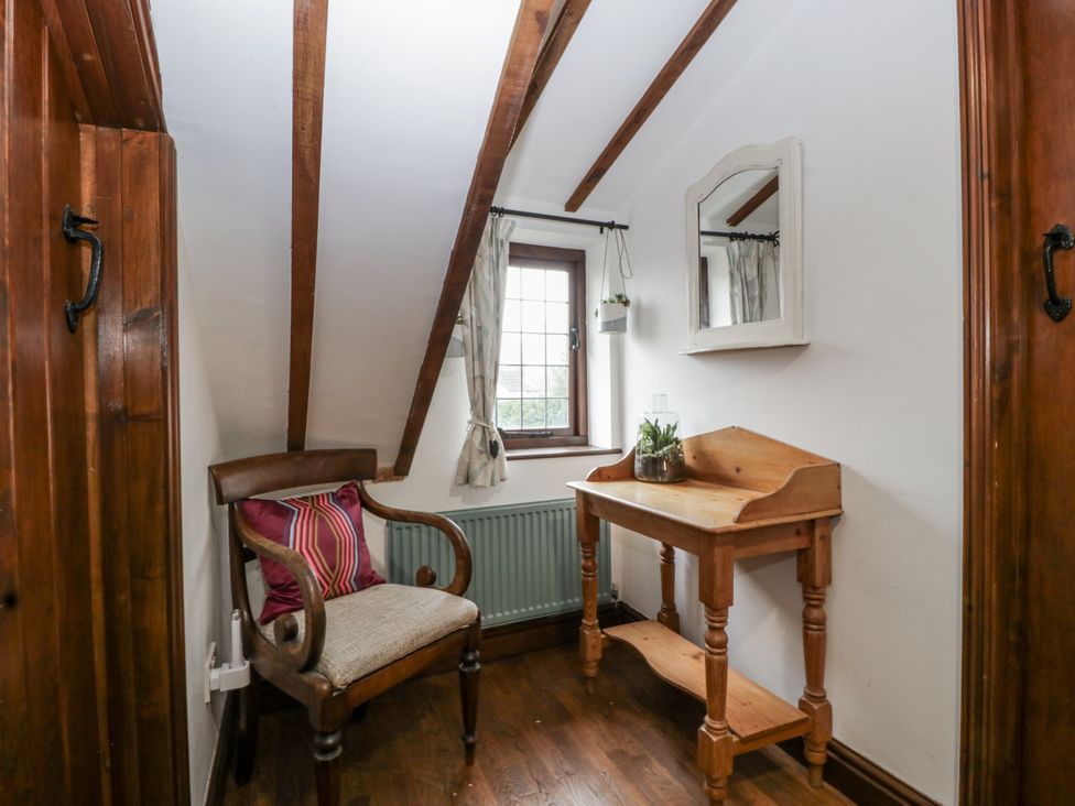 A corner with a chair and a table with a plant at Magpie Cottage in Worcester