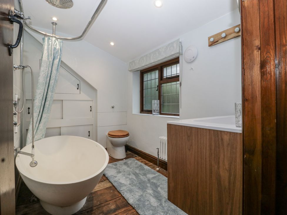 A bathroom with a bath tub, toilet, and sink at Magpie Cottage Worcester