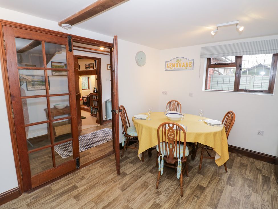 A dining room with a yellow tablecloth and chairs at Magpie Cottage Powick near Callow End