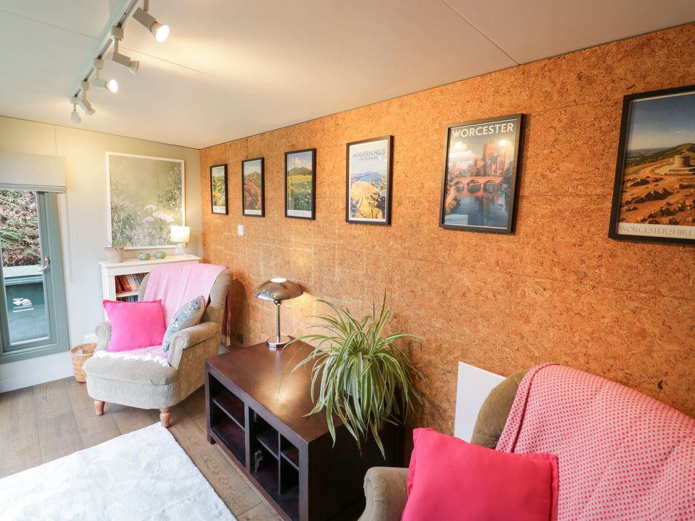A sitting room with posters on the wall and a plant at Magpie Cottage, Powick near Callow End