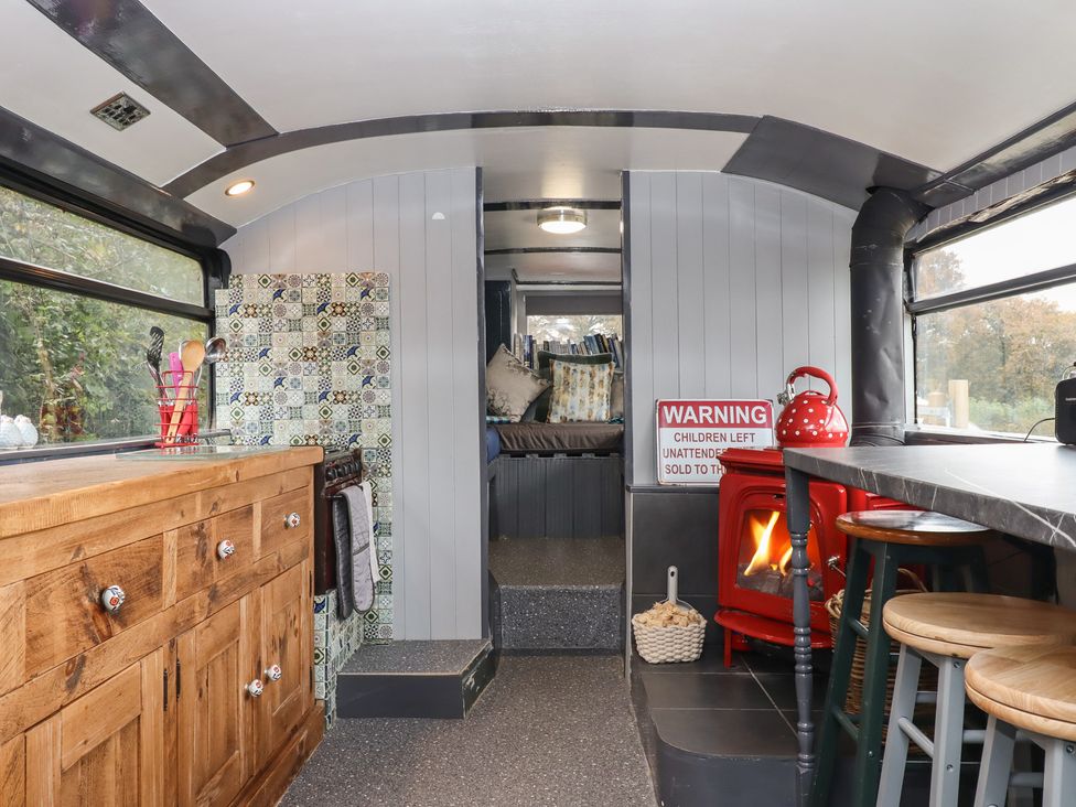 A living room with a wooden cabinet and stove at The Bus on the Hill