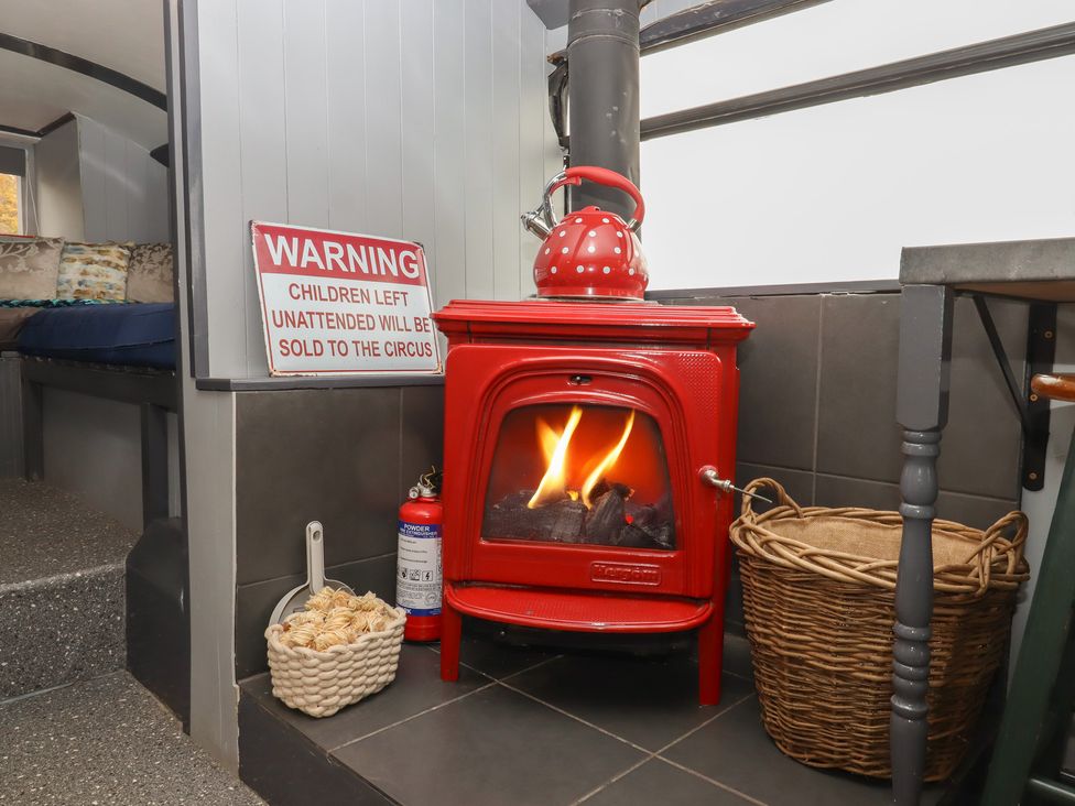 A wood stove with flames and a warning sign in a living room at The Bus on the Hill