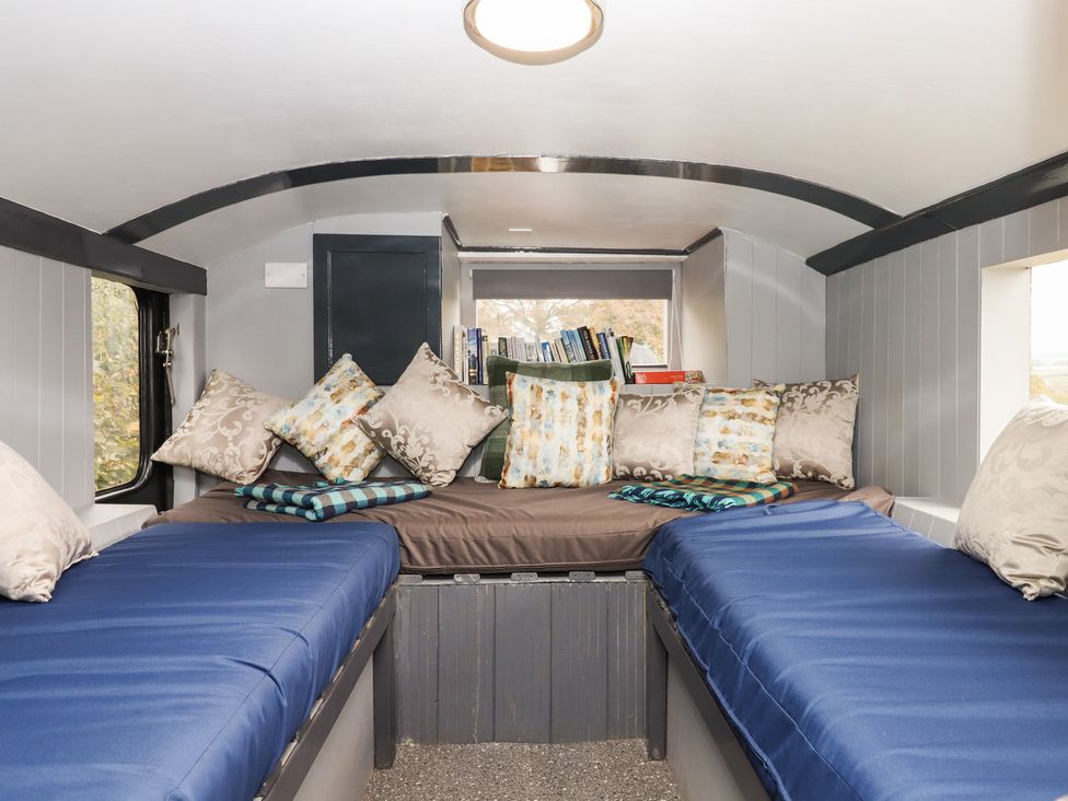 A sleeping area with two beds and shelves filled with books at The Bus on the Hill