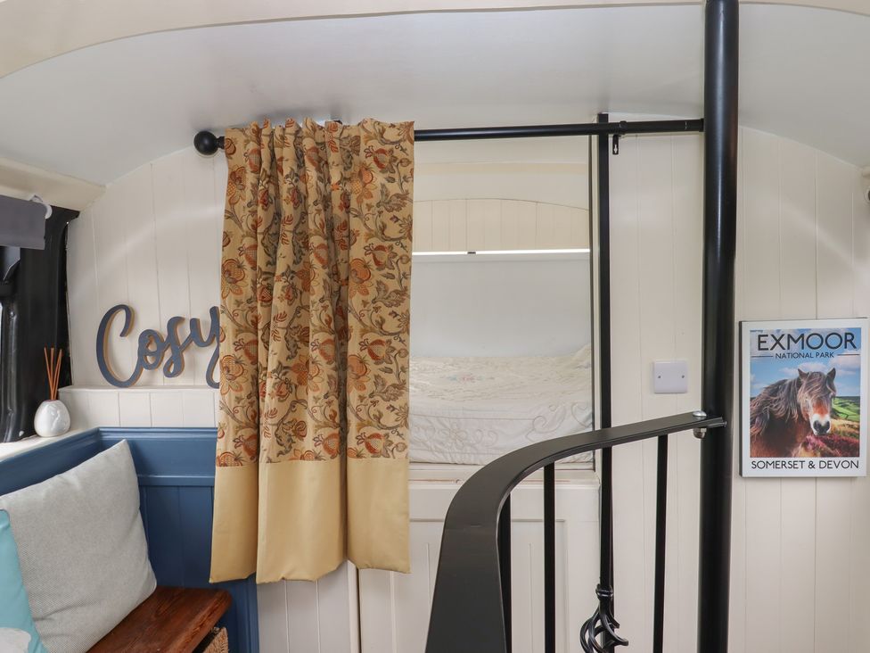 A sleeping area with a sofa and spiral staircase at The Bus on the Hill