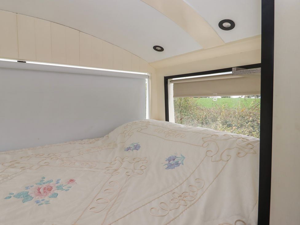 A sleeping area with a bed and windows at The Bus on the Hill