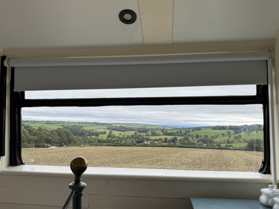 A view from a window showing fields and trees at The Bus on the Hill in Huntsham near Bampton, Devon