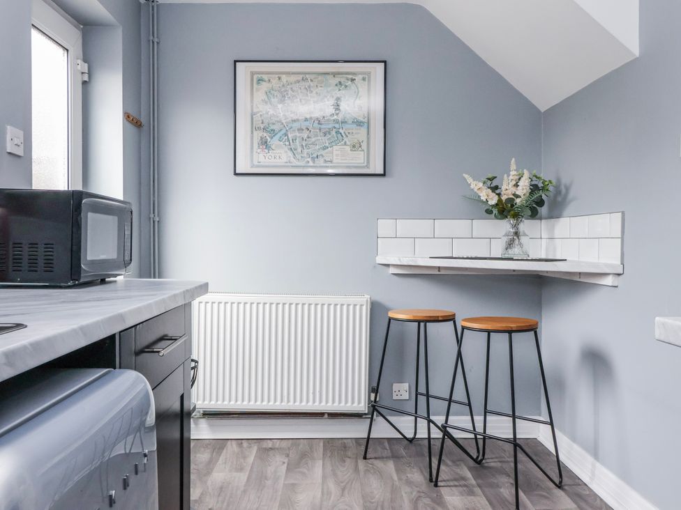 A kitchen with a microwave, bar stools, and framed map at 127 Bellhouse Way York