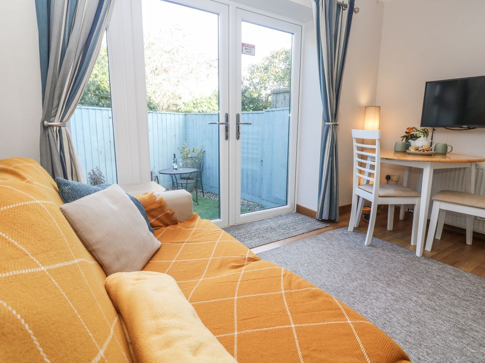 A living room with a sofa and dining area at Blake Lodge in Crantock