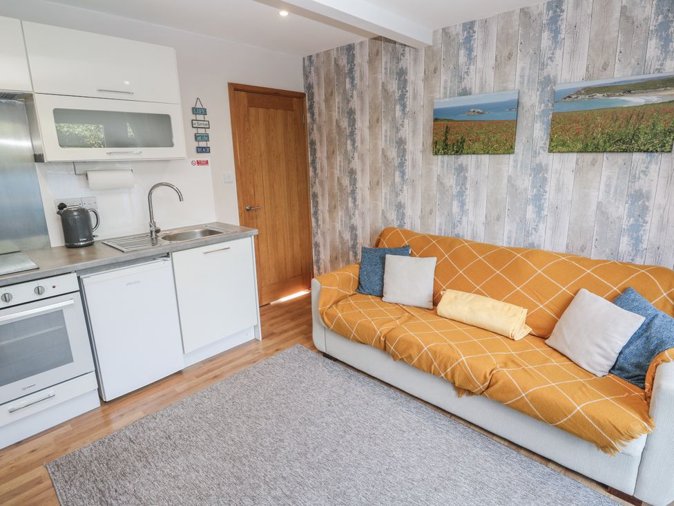 A living room with a sofa and kitchen area at Blake Lodge in Crantock